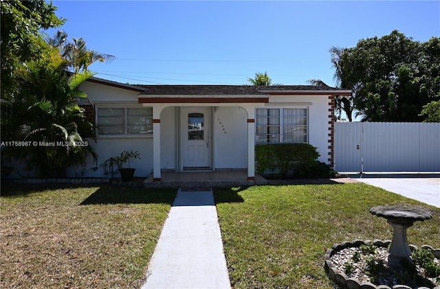 view of front of house featuring a gate, fence, a front lawn, and stucco siding