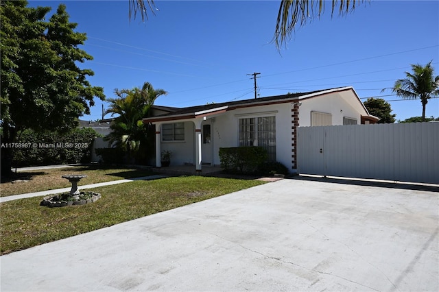 view of front of property with a front yard, a gate, fence, and stucco siding