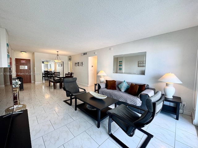 living room with visible vents, a textured ceiling, and marble finish floor