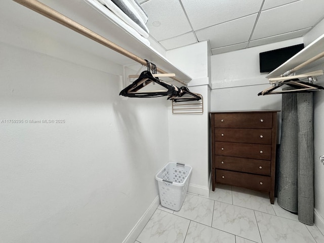 spacious closet with marble finish floor and a drop ceiling