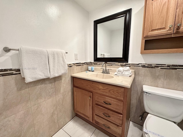 bathroom featuring tile walls, toilet, wainscoting, marble finish floor, and vanity
