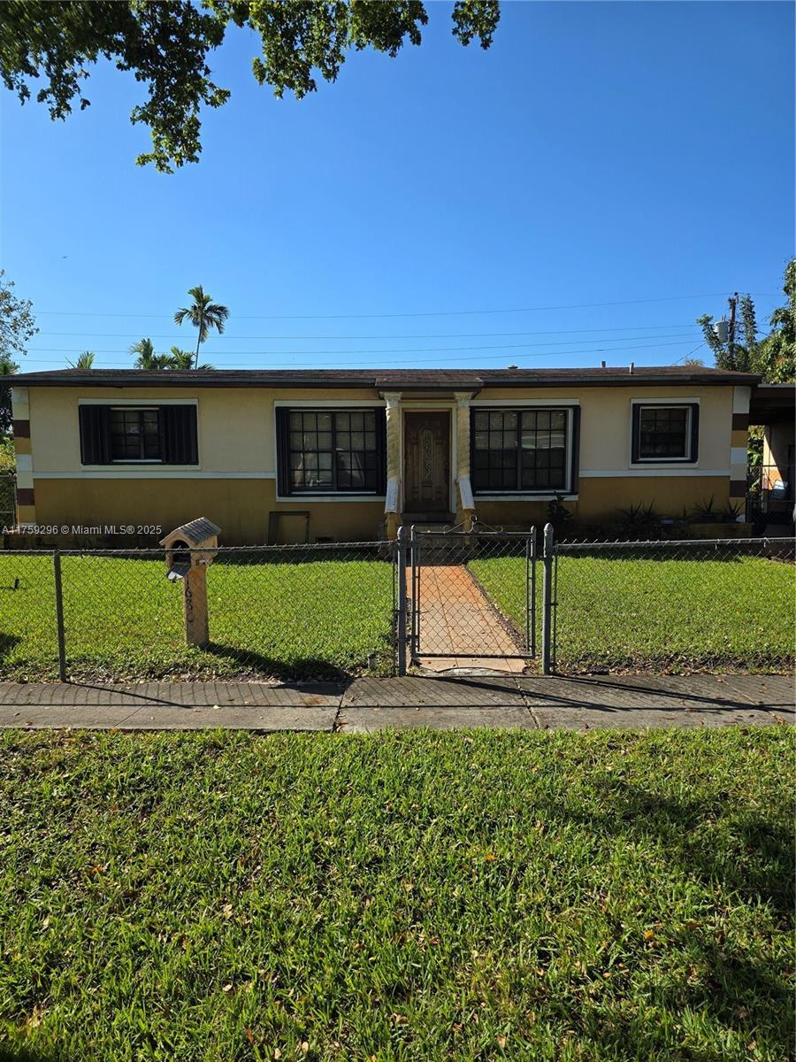 1680 NE 159th St, North Miami Beach, FL 33162 - ranch-style house featuring a fenced front yard, a gate, a front lawn, and stucco siding