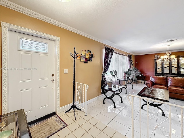 foyer featuring light tile patterned floors, visible vents, baseboards, ornamental molding, and a chandelier