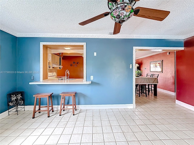 kitchen featuring a textured ceiling, light tile patterned flooring, range with electric stovetop, a sink, and a ceiling fan