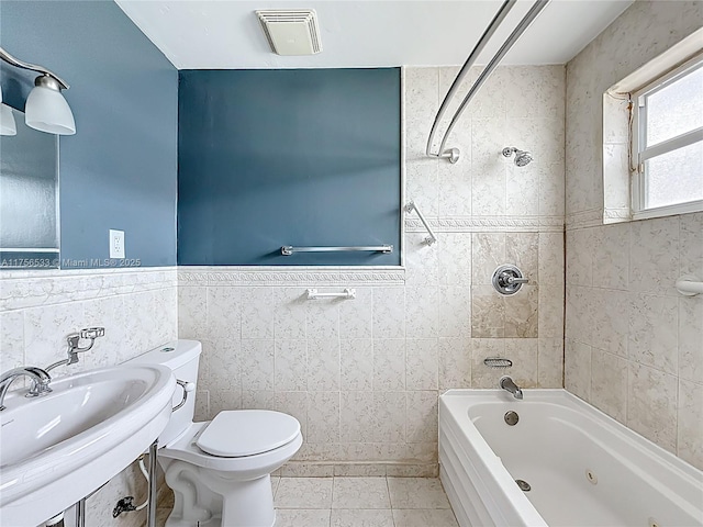 bathroom featuring toilet, a sink, visible vents, tile walls, and a combined bath / shower with jetted tub