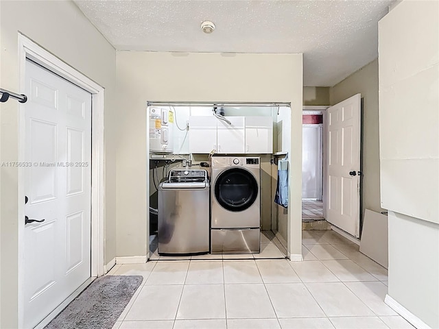 laundry room featuring laundry area, washer and clothes dryer, a textured ceiling, and light tile patterned floors