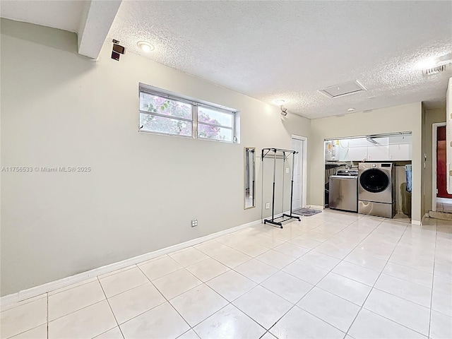 interior space with light tile patterned floors, visible vents, baseboards, a textured ceiling, and washing machine and dryer