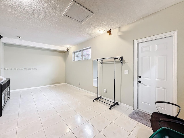 interior space with a textured ceiling, light tile patterned flooring, and baseboards