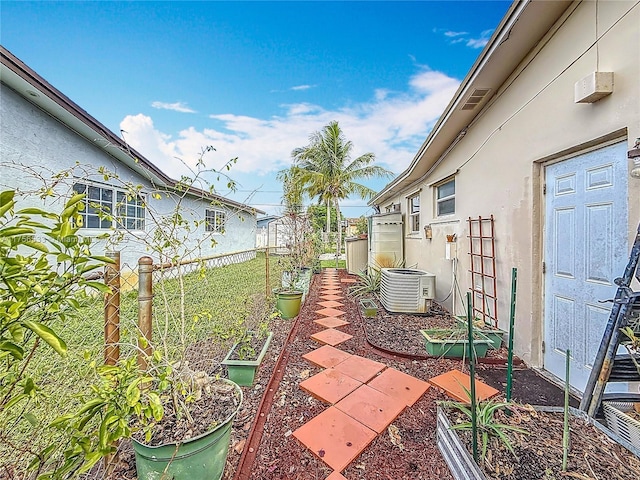 view of yard with a garden, central AC, and fence