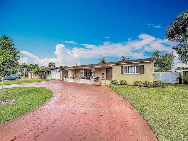 ranch-style house with a porch, fence, driveway, stucco siding, and a front yard