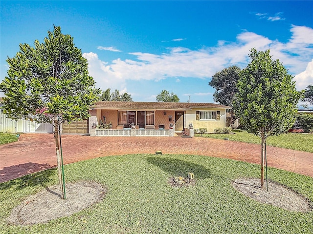 ranch-style house featuring decorative driveway, a front yard, covered porch, and a garage