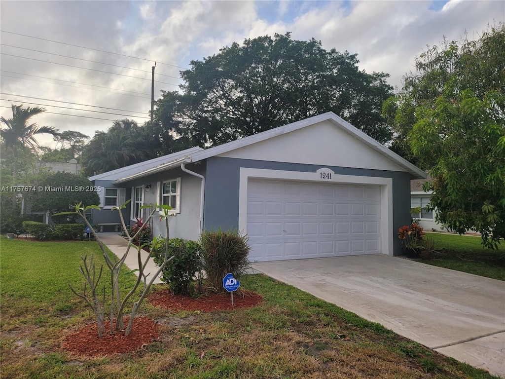 view of front of house with a garage, driveway, a front yard, and stucco siding