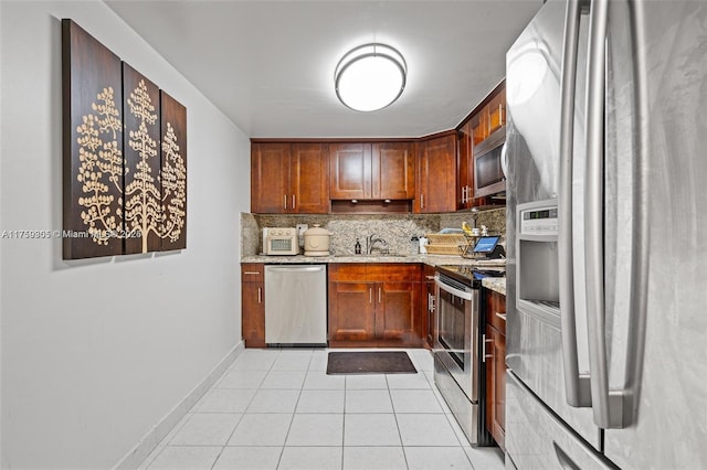 kitchen with light tile patterned floors, decorative backsplash, appliances with stainless steel finishes, light stone counters, and a sink