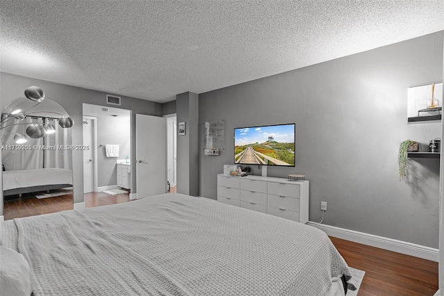 bedroom featuring visible vents, connected bathroom, a textured ceiling, wood finished floors, and baseboards