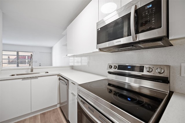 kitchen with open shelves, light countertops, appliances with stainless steel finishes, white cabinetry, and light wood-type flooring