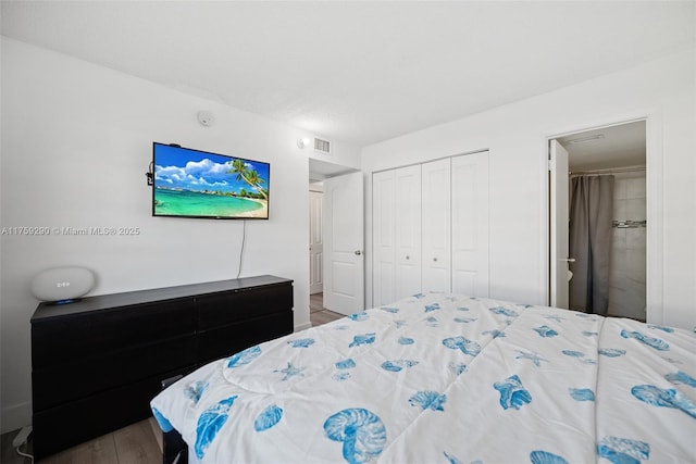 bedroom with a closet, wood finished floors, and visible vents