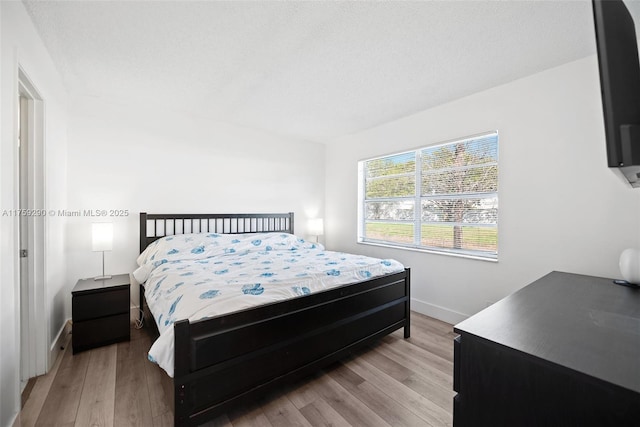 bedroom featuring light wood finished floors and baseboards