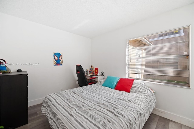 bedroom featuring a textured ceiling, wood finished floors, and baseboards