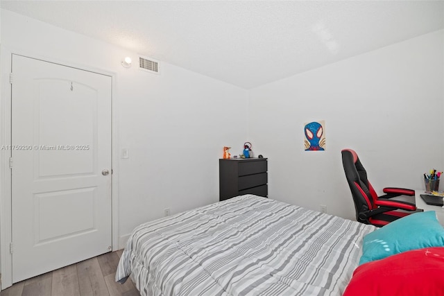 bedroom featuring visible vents and wood finished floors