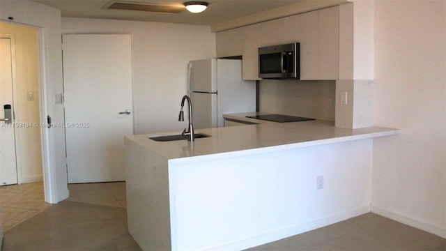 2889 Mcfarlane Rd Unit 1511, Miami, FL 33133 - kitchen featuring a peninsula, a sink, light countertops, freestanding refrigerator, and stainless steel microwave