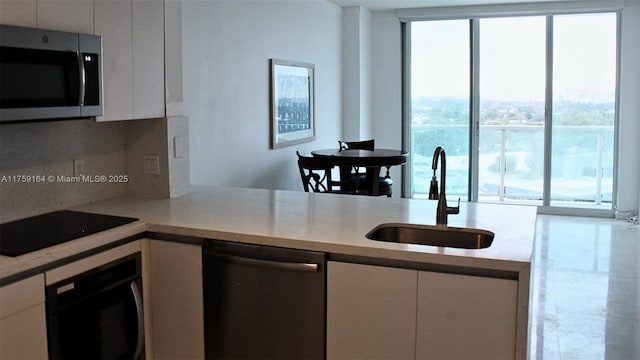 2889 Mcfarlane Rd Unit 1511, Miami, FL 33133 - kitchen with light countertops, appliances with stainless steel finishes, a sink, and white cabinets