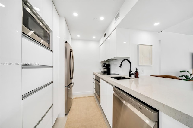 kitchen featuring modern cabinets, white cabinetry, stainless steel appliances, and a sink