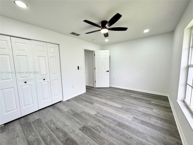 unfurnished bedroom featuring recessed lighting, a closet, visible vents, wood finished floors, and baseboards