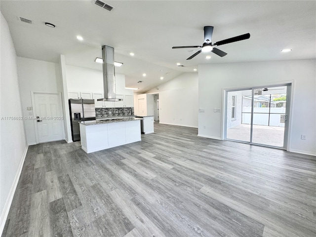 kitchen featuring a kitchen island, visible vents, open floor plan, vaulted ceiling, and stainless steel refrigerator with ice dispenser