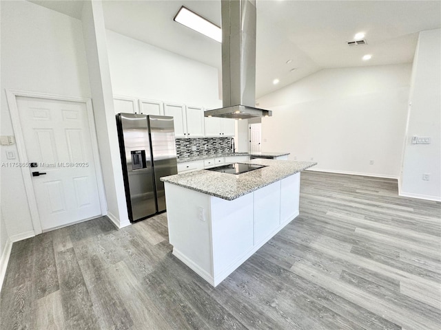 kitchen with light wood-type flooring, black electric cooktop, island range hood, and stainless steel refrigerator with ice dispenser