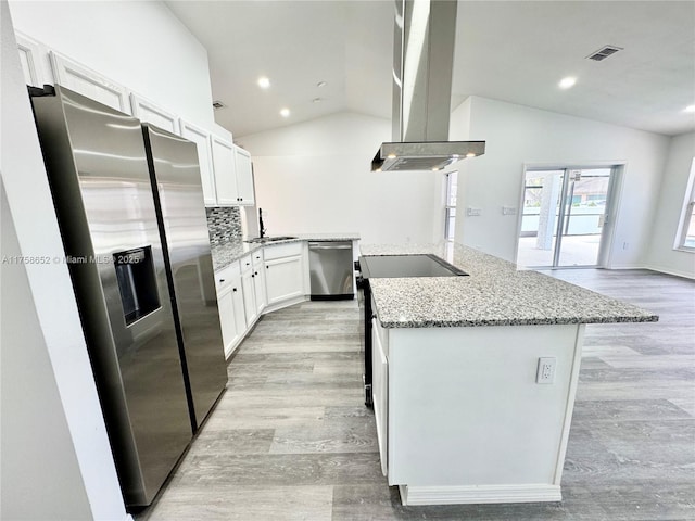 kitchen with stainless steel appliances, lofted ceiling, a center island with sink, and exhaust hood