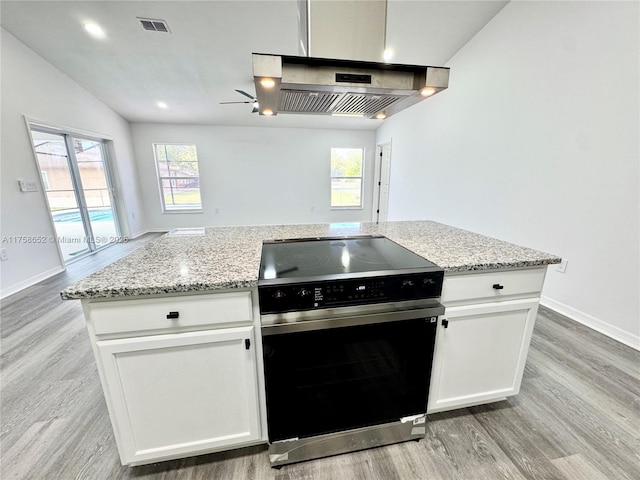 kitchen with extractor fan, light wood-style floors, electric range, and light stone countertops