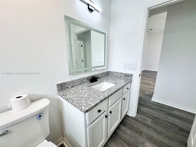 bathroom with vanity, wood finished floors, toilet, and baseboards