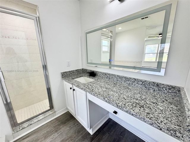 full bathroom with a stall shower, visible vents, baseboards, wood finished floors, and vanity