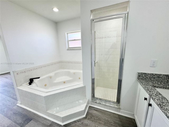 full bathroom with a jetted tub, a stall shower, wood finished floors, and vanity