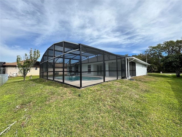 rear view of property with a yard, a patio area, glass enclosure, and an outdoor pool