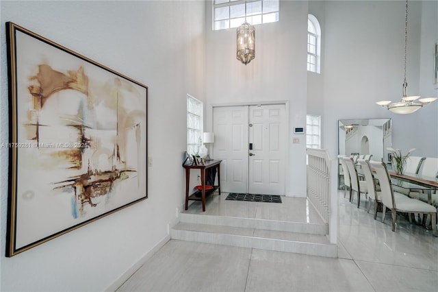 foyer entrance featuring a towering ceiling, plenty of natural light, and a chandelier