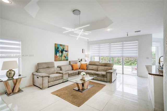 living area featuring light tile patterned floors, recessed lighting, visible vents, a tray ceiling, and an inviting chandelier