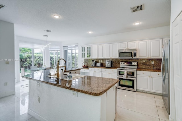 kitchen featuring visible vents, backsplash, appliances with stainless steel finishes, white cabinetry, and a sink