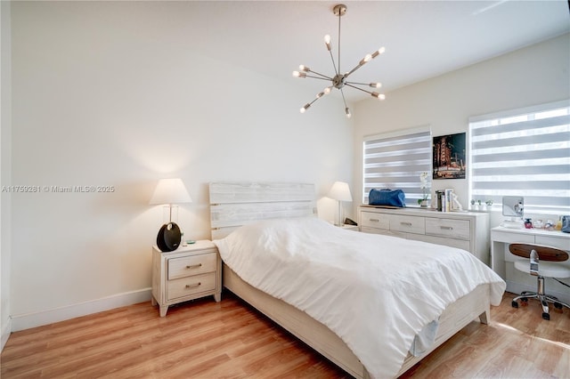 bedroom featuring light wood finished floors, baseboards, and a chandelier