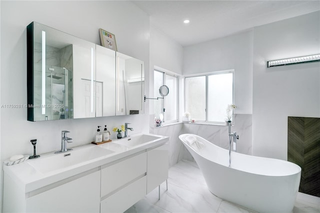 full bath with a sink, a freestanding bath, marble finish floor, a shower stall, and double vanity