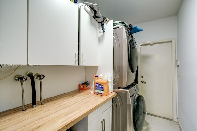 laundry room featuring stacked washer and clothes dryer and cabinet space