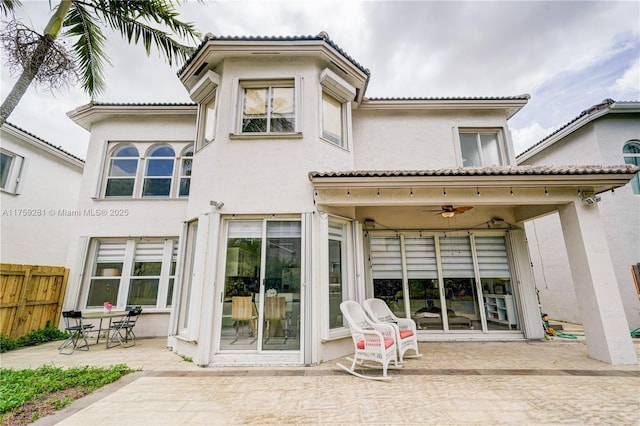 rear view of property with stucco siding, fence, and a patio