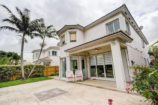 rear view of property with a ceiling fan, stucco siding, a patio, and fence