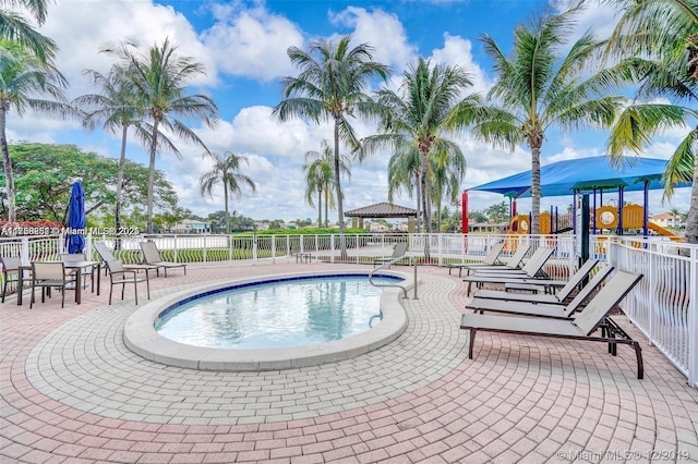 view of swimming pool with playground community, a patio, and fence