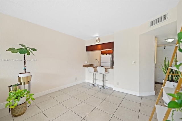 spare room featuring visible vents, a sink, baseboards, and light tile patterned flooring