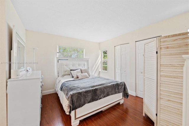 bedroom with baseboards, dark wood-style flooring, and multiple closets