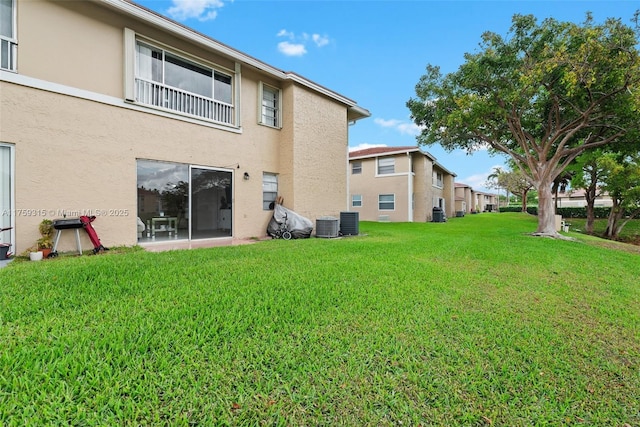 rear view of property featuring a yard, cooling unit, and stucco siding