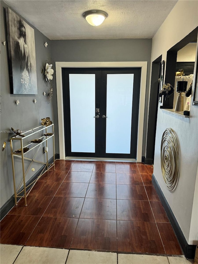 interior space featuring french doors, baseboards, a textured ceiling, and wood finished floors