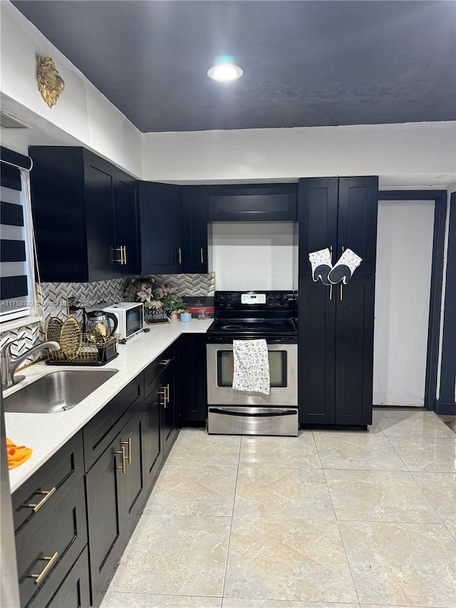 kitchen featuring decorative backsplash, stainless steel electric range oven, light countertops, and a sink