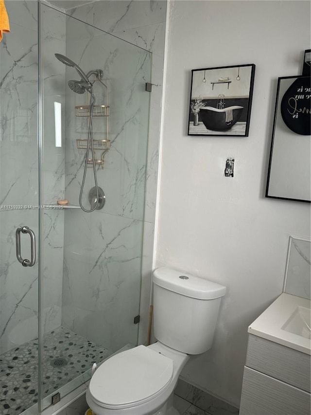 full bath featuring a marble finish shower, marble finish floor, toilet, and vanity